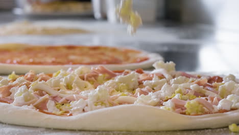 close up of an unrecognizable chef adding cheese on the pizza raw dough at restaurant