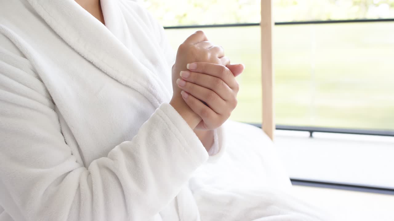 Hands are placing one over other, rubbing palms and fingers on bed near window to soothe