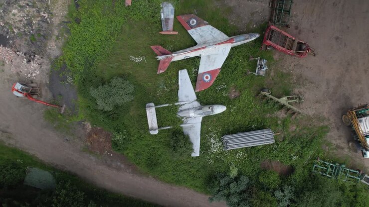 Aerial descent to the abandoned RAF military jets standing on the green field