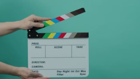 clapperboard golpeando. pizarra de película de película. cerrar la mano aplaudiendo pizarra de filmación vacía en fondo de color pantalla azul o verde. dentro y fuera de pizarra de películas cortando para producción de video. filmación o rodaje de películas.