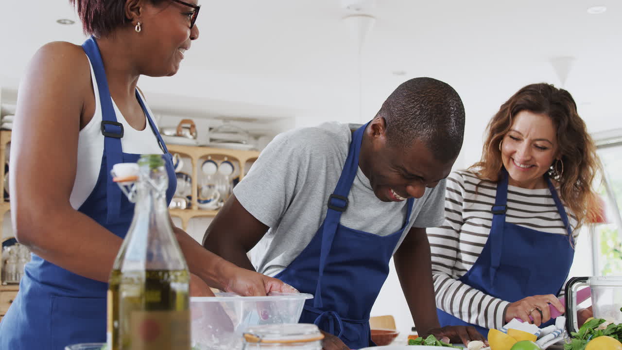 Male And Female Adult Students Preparing Ingredients For Dish In Kitchen Cookery Class