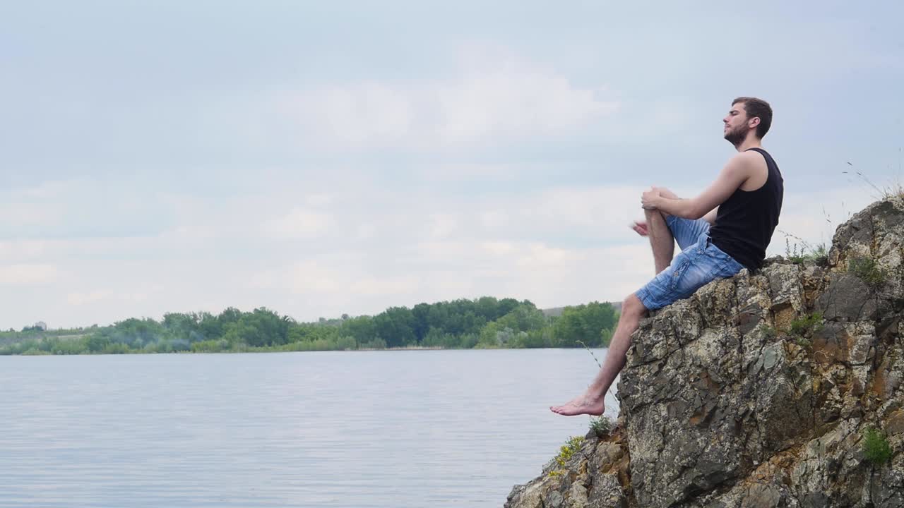 강 의 바위 위에 앉아 있는 남자