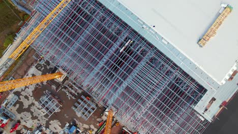rotating bird's eye view of steel building being built on at construction site, drone shot
