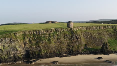 Drone-Aerial-View-of-Mussenden-Temple,-Clifftop-Landmark-Above-Atlantic-Ocean-on-Northern-Ireland-Coastline,-UK