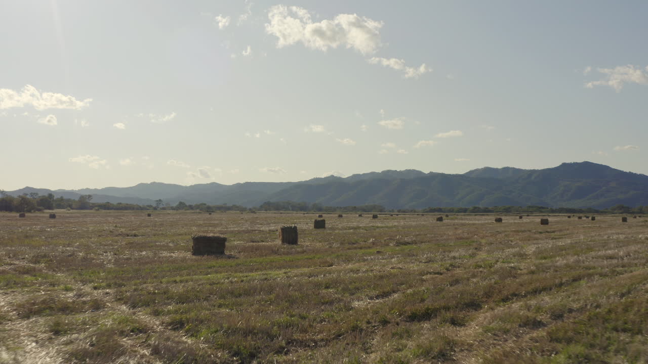 volar sobre montones de heno en el campo con la cresta de la montaña en el fondo en un día brillante, claro y soleado
