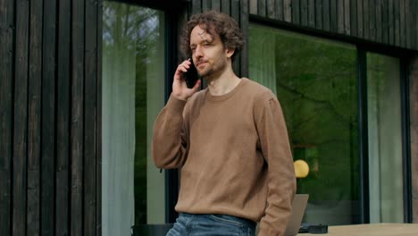 man talking on phone outside modern house