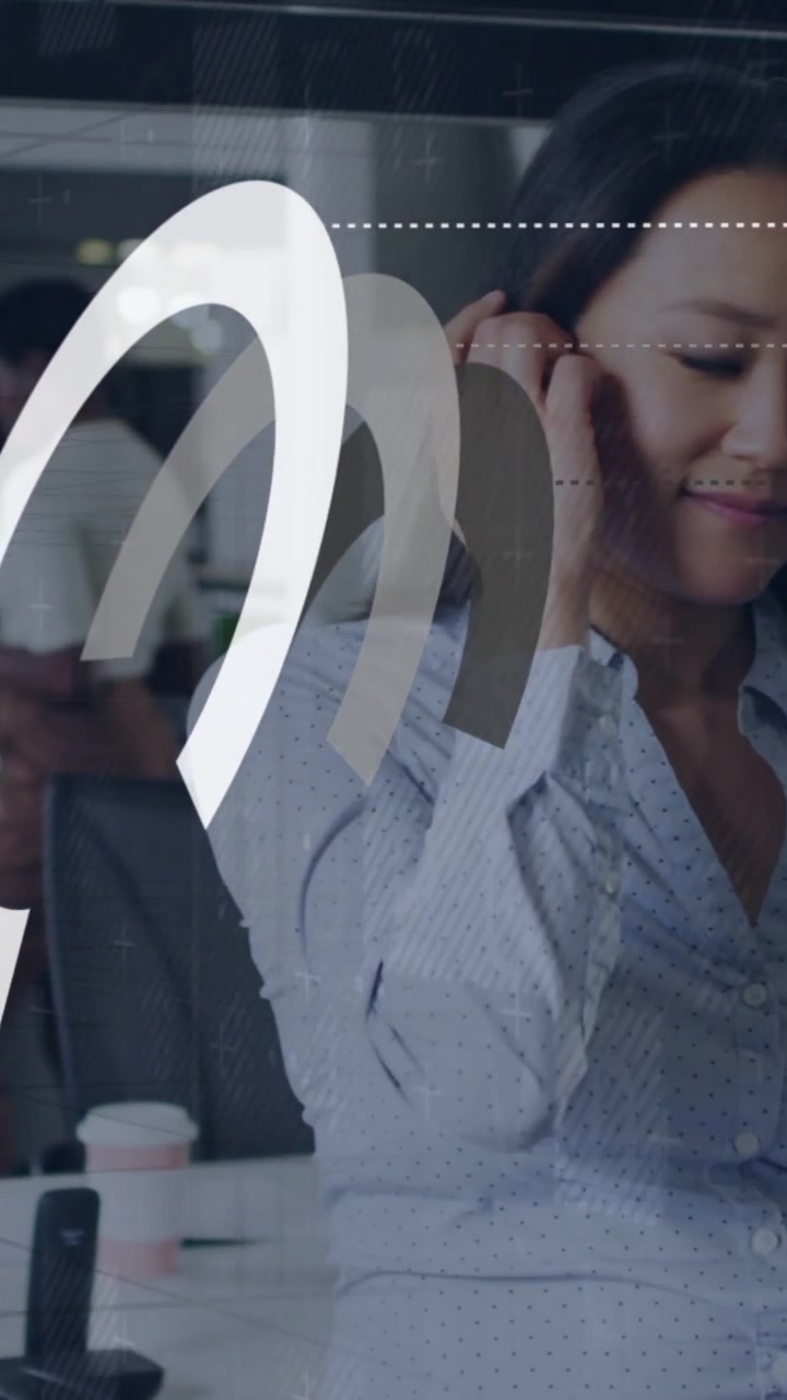 Vertical video: Office worker tapping device, arcs sliding left and adjusting earbud to answer call
