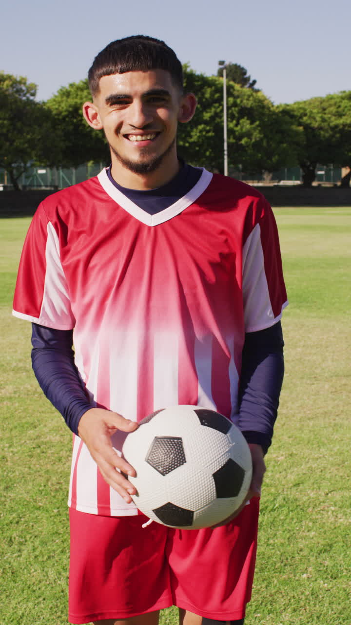 video vertical de un jugador de fútbol biracial con la pelota en el campo