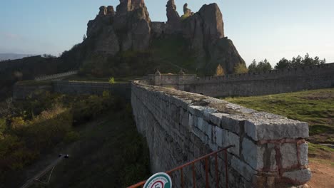 A-reveal-shot-of-the-historical-Belogradchik-Fortress-and-rock-formation-in-Bulgaria-on-a-clear-blue-sky-sunny-day