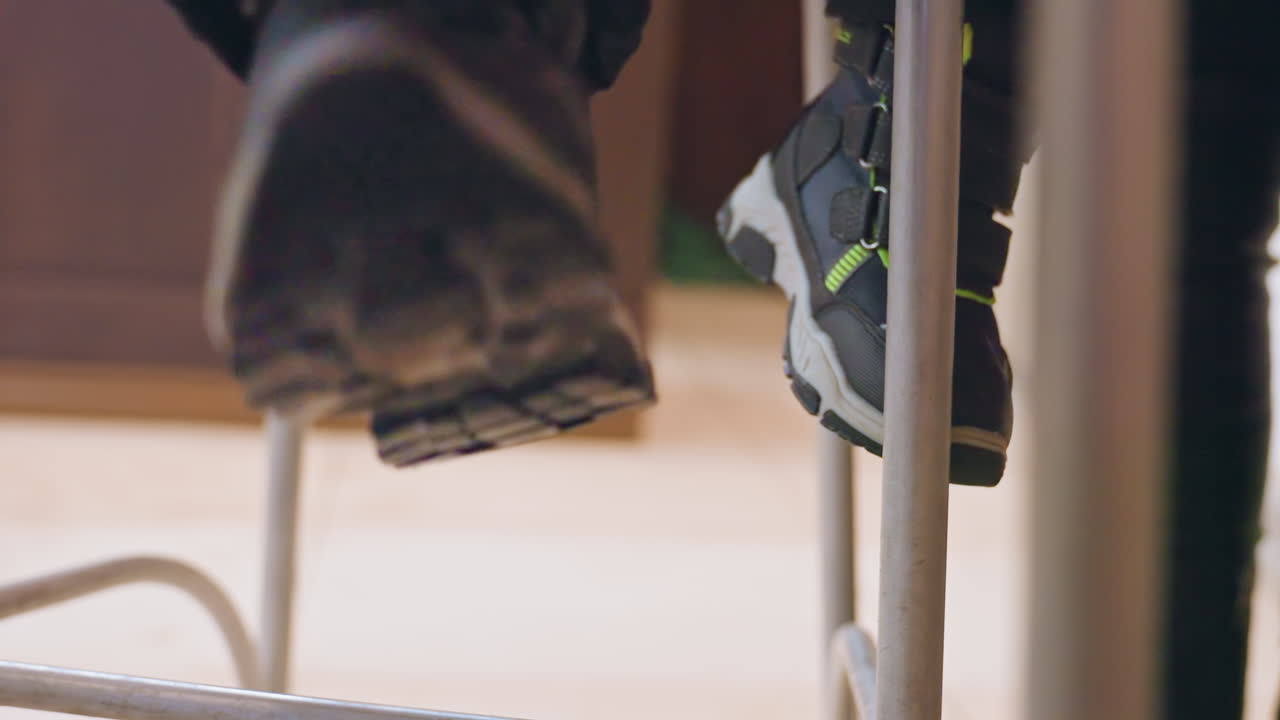 Small sneakers dangling under kitchen counter, young son sits on high stool while mother prepares meal, closeup of black shoes with neon green accents, gentle warm light, quiet domestic waiting, soft