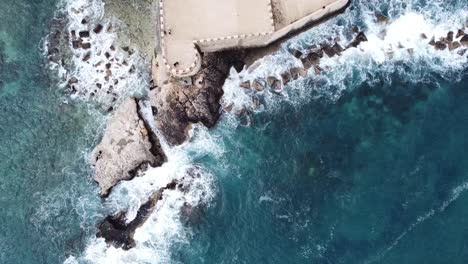 View-from-above-of-a-medieval-tower-whose-rocks-defy-the-waves-of-crystal-blue-sea