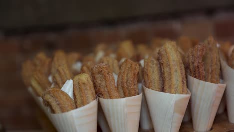 fried sugar coated churros for sale in white paper cones