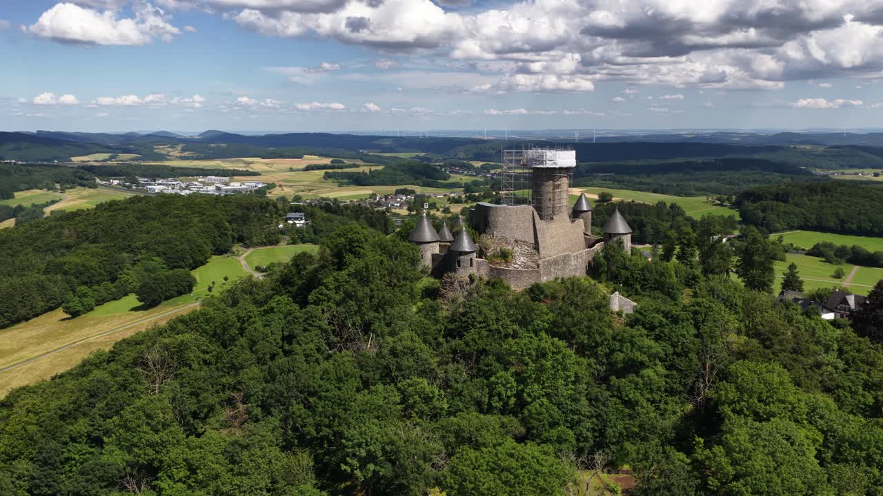 Nurburg castle, ruins of ancient castle on top of hill. Race track Nurburgring surrounding the monument. Aerial video