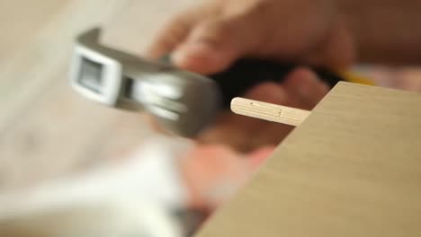 using a hammer to install a wooden dowel