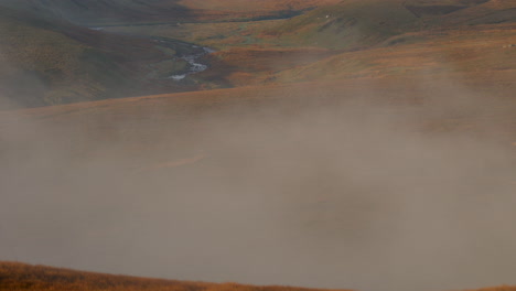 early morning mist hanging over the moorlands in the yorkshire dales national park tilt up shot