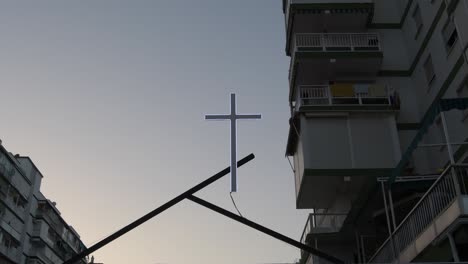 cross illuminated between building at sunset