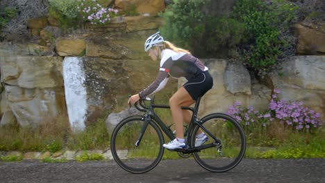 ciclista femenina en bicicleta en un camino de campo junto a la roca 4k