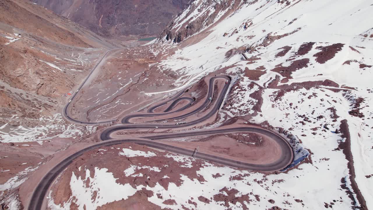 Vehicles Driving On Dangerous Hairpin Road On Snowy Mountains Of Los Andes In Chile