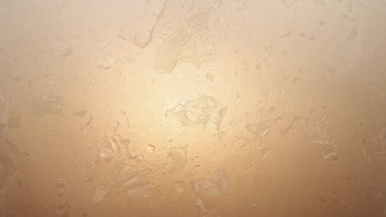 Primo piano di un pannello ruvido che reagisce al tremolio caldo della retroilluminazione, con goccioline e graffi