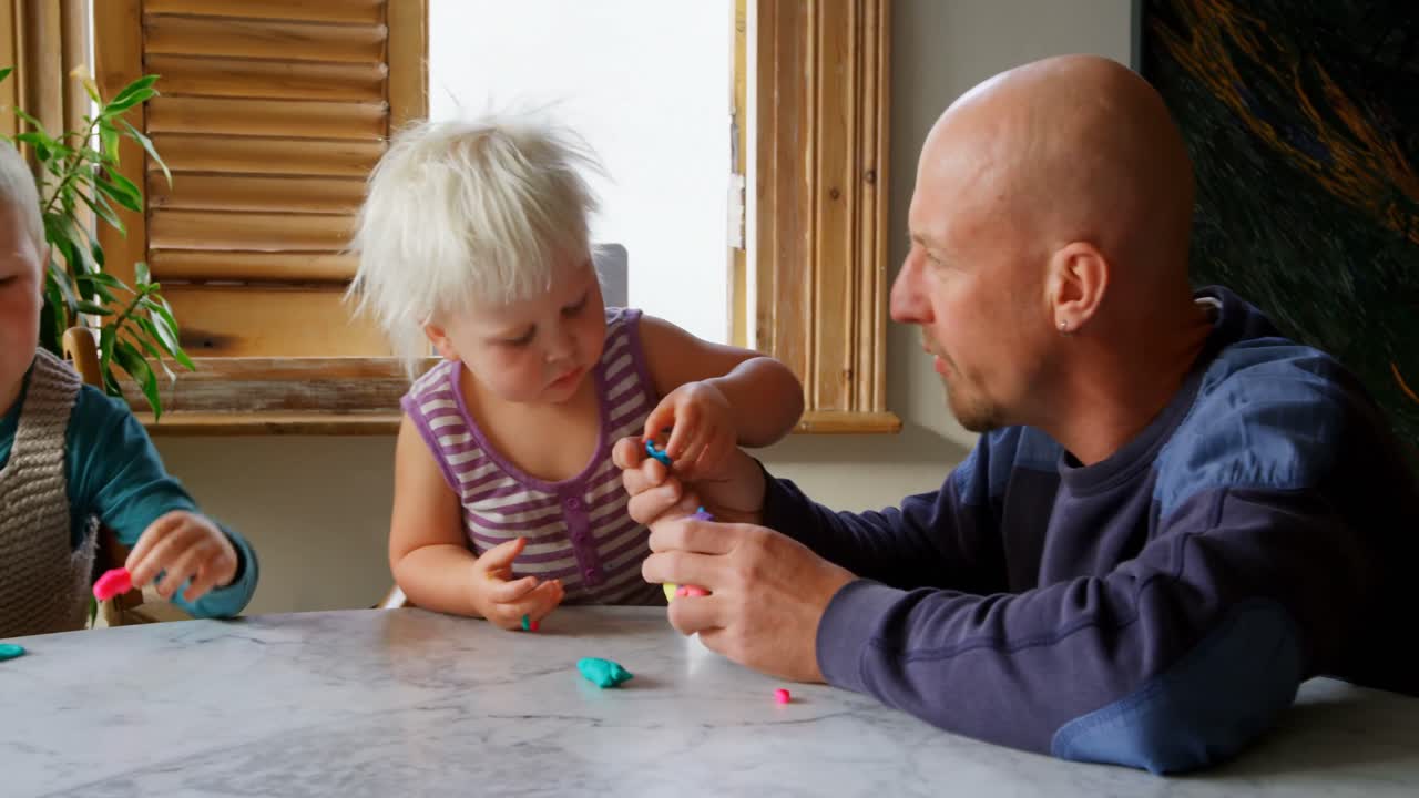 Far og børn leger sammen med modellervoks i et hyggeligt hjem 4k