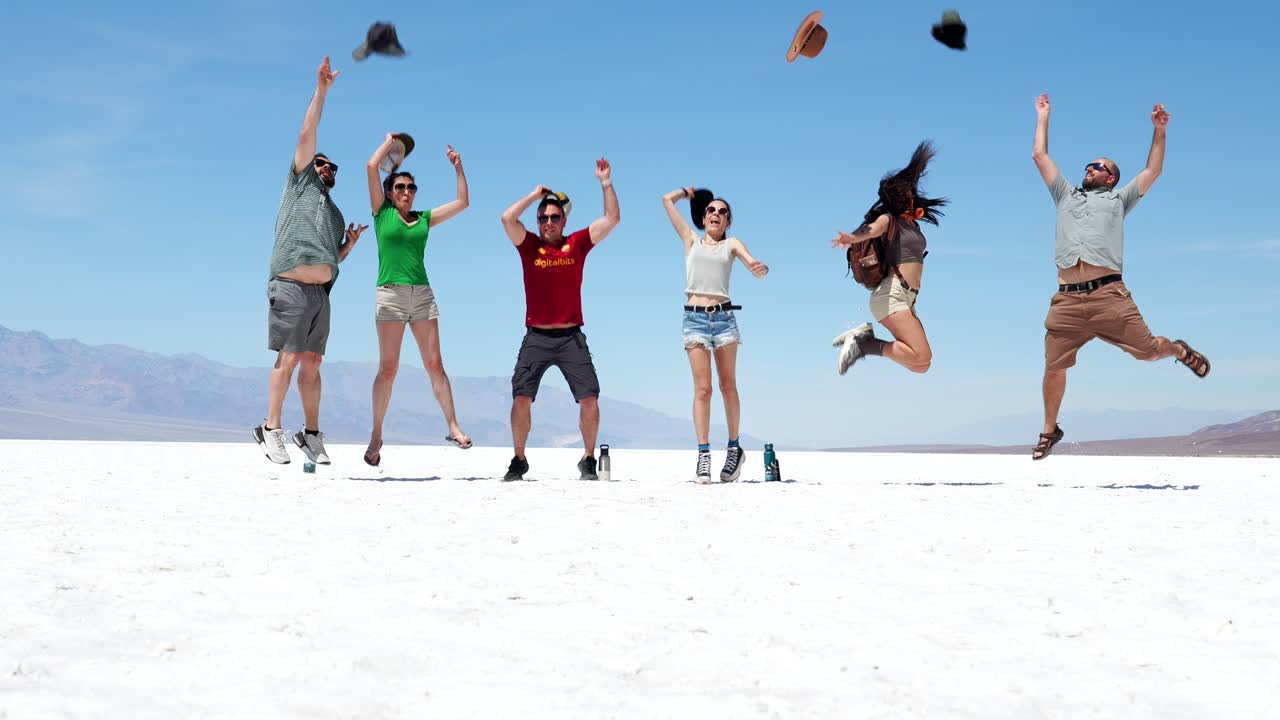 Gruppo di amici gioiosi che saltano su una piana di sale bianca nel deserto