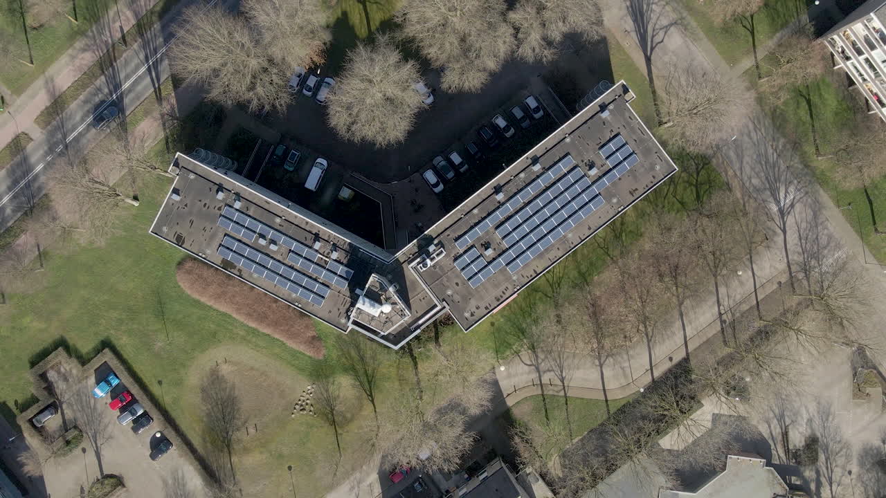 Top down aerial of solar panels on large apartment building rooftop