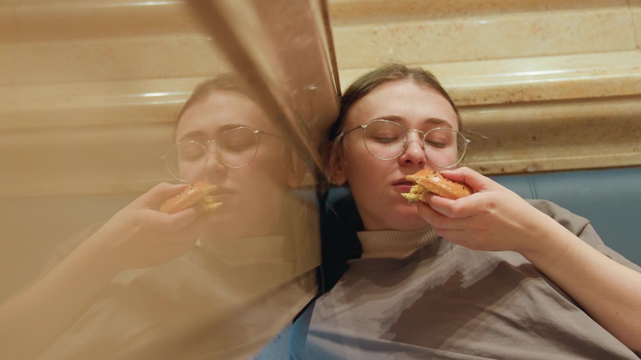 City woman snacks at night. Reflective lady relaxes with pizza downtown. Thoughtful woman savoring food in urban nighttime setting. Quiet woman enjoying meal amidst lively city lights at night