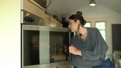 young woman placing baking tin in oven