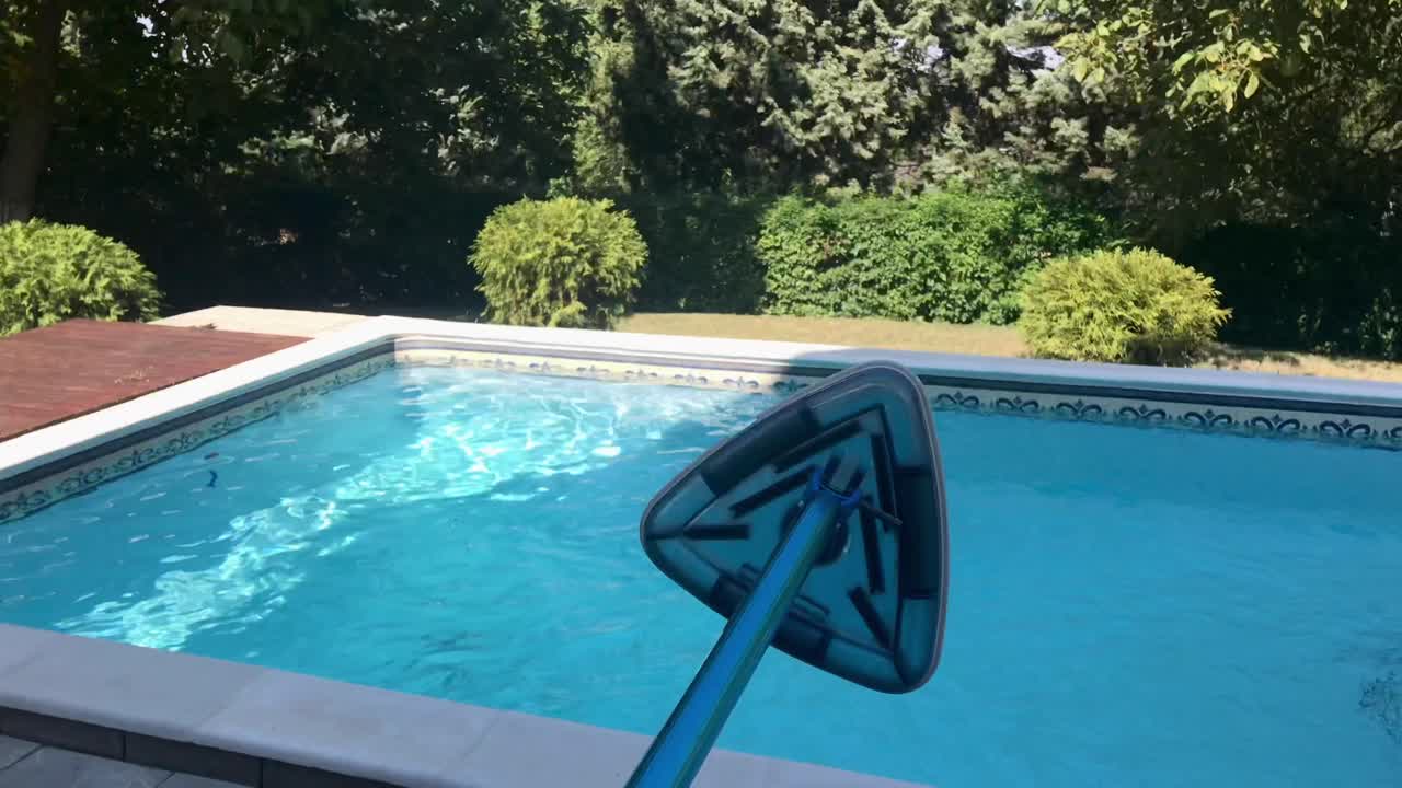 Adjusting metallic blue telescopic pool vacuum pole for vacuuming outdoor swimming pool