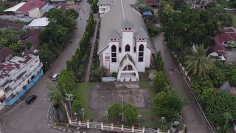 Drone-flies-over-a-big-church-at-Waikaboebak-city-with-traffic-on-the-roads,-aerial