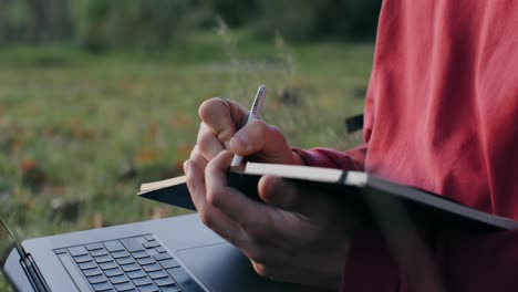 person writing in a notebook outdoors