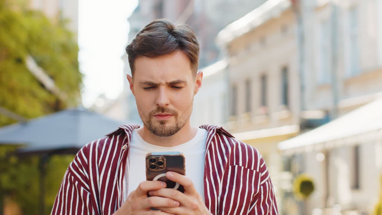 Surprised handsome man use smartphone loses bad news fortune loss fail outdoors in city street