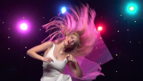 woman dancing energetically under colorful lights
