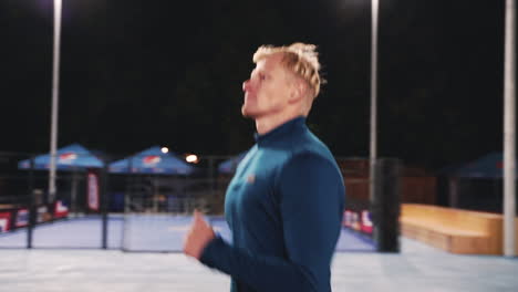 focused blond man running in the park at night