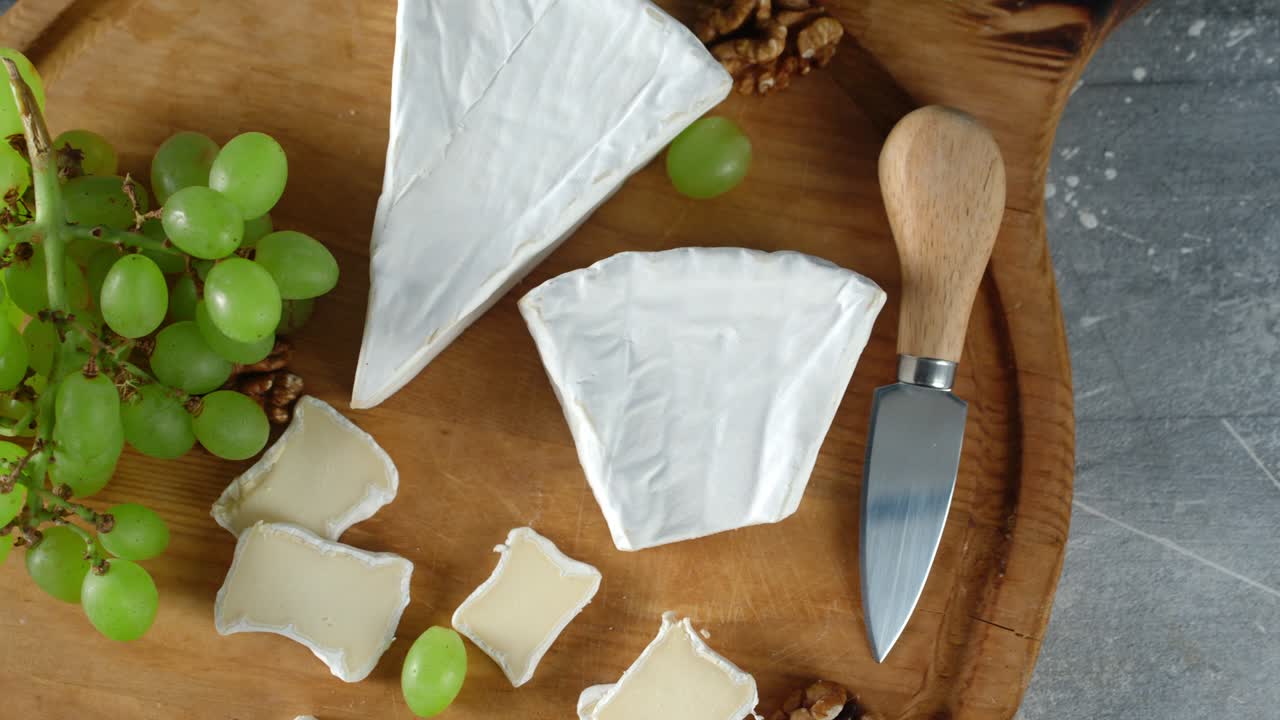 нарезанный сыр камамбер с виноградом на доске для резки.
