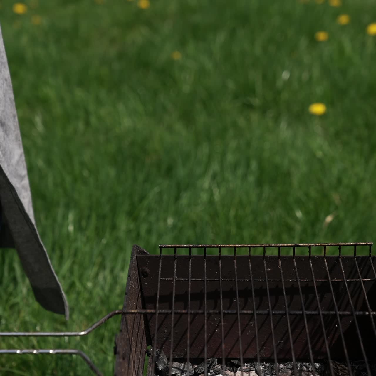 Man on picnic prepares juicy sausages in barbecue. Chef putting ready roasted hot dog sausages into a plate in the garden