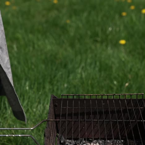 man on picnic prepares juicy sausages in barbecue. chef putting ready roasted hot dog sausages into a plate in the garden