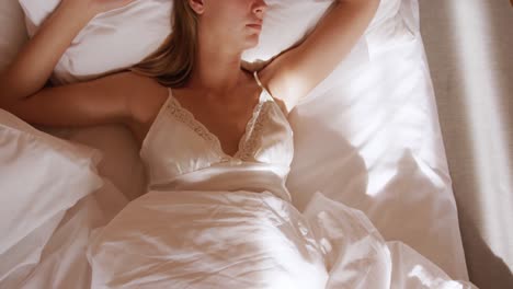 mujer caucásica descansando en la cama en una habitación de hotel