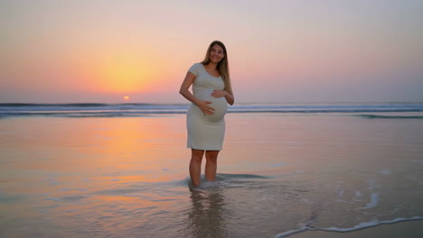 pregnant woman enjoying sunset at the beach