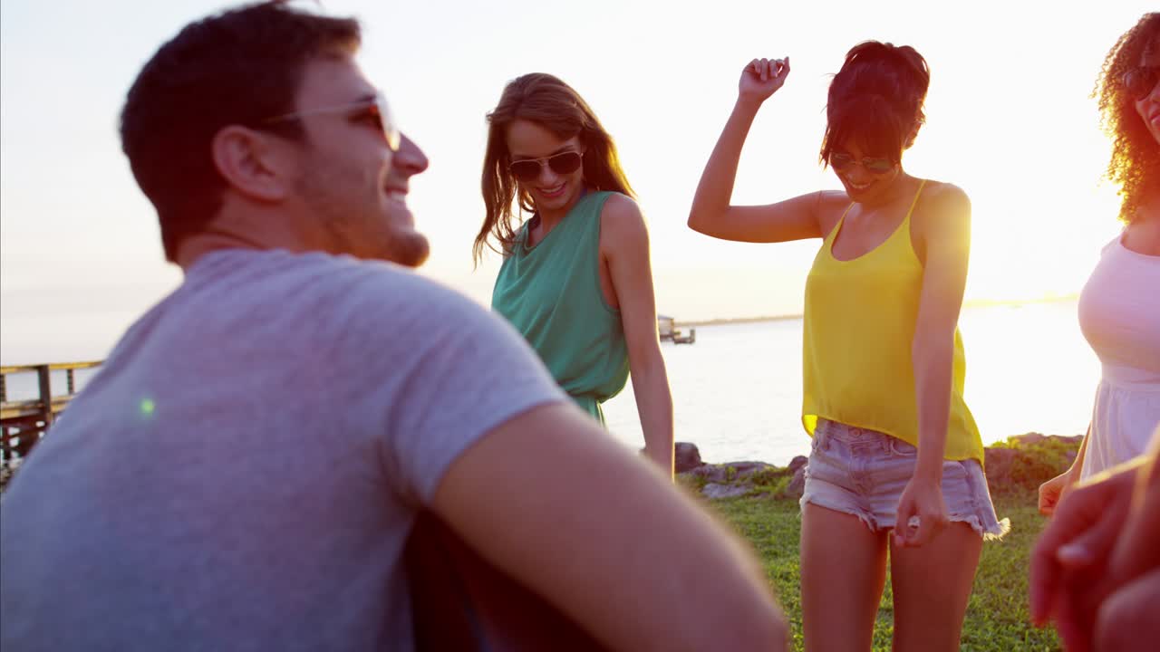 hombre caucásico tocando la guitarra en la playa al atardecer