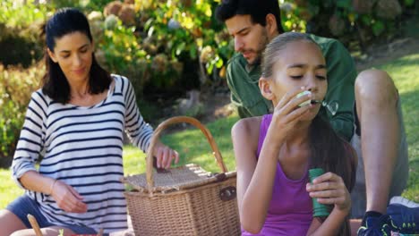 girl blowing bubble while her parents sitting in background 4k