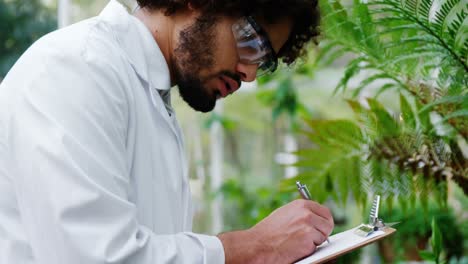 man taking notes of plants on clipboard