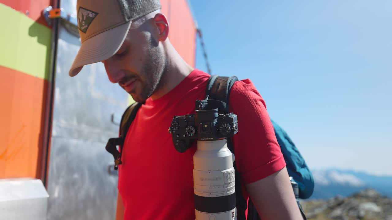 viajero masculino montando una cámara en la correa de la mochila en cima fontana en sondrio, italia