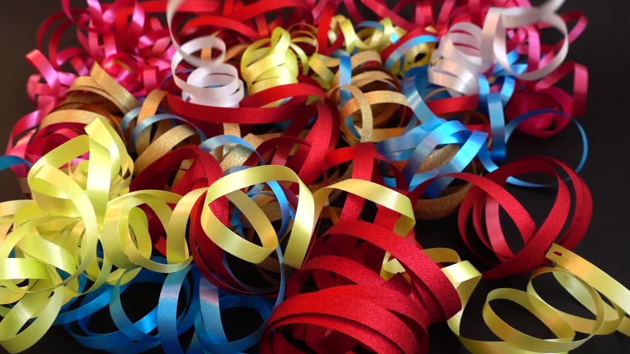 Fitas e Serpentinas Coloridas de Festa Caindo em um Fundo Escuro