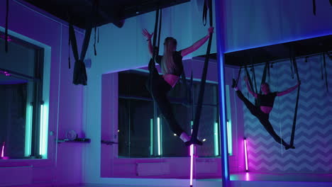 entrenamiento de fly-yoga para estirar las piernas mujer está haciendo split en hamaca por encima del suelo yoga aéreo