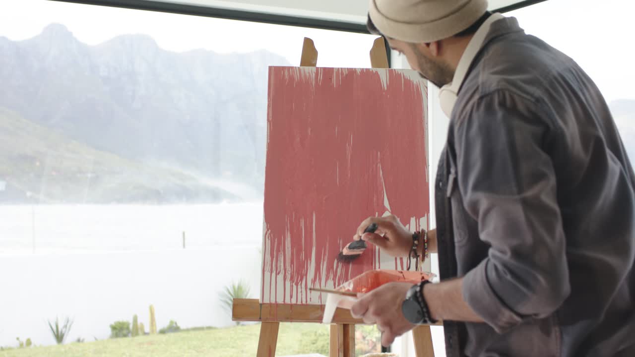 कैनवस पर गुलाबी रंग से डूबा हुआ पेंटब्रश दबाकर सतह को रंग से संतृप्त करते हुए स्ट्रोक की परतें बनाता है।