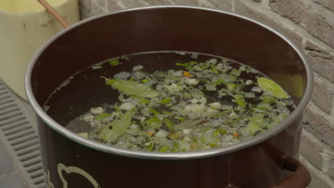 preparar una olla grande de caldo de pollo fresco como ingrediente inicial para hervir el arroz en un plato de paella