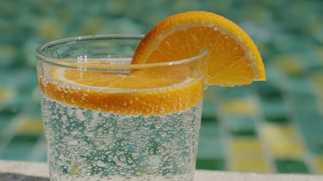 Refreshing Sparkling Beverage with Orange Slice Overlooking a Beautiful Background of Aqua Tiles in a Poolside Setting for Ultimate Enjoyment