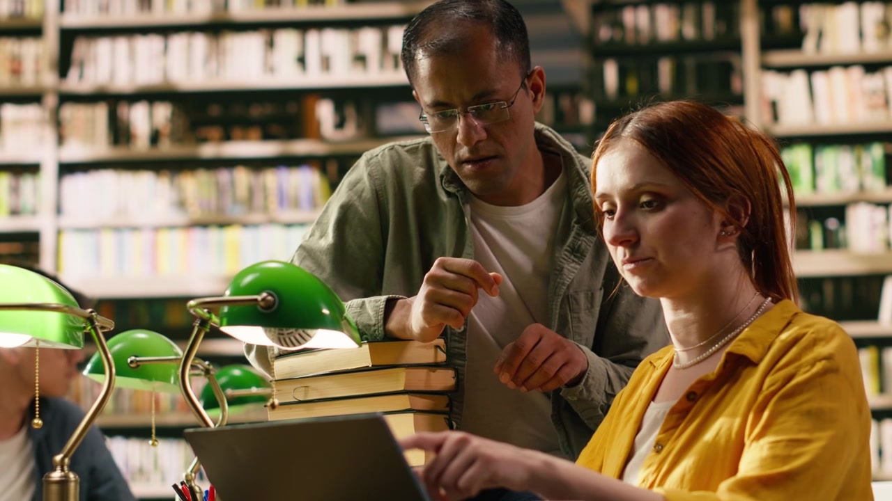 Tutor explaining assignment to student and pointing at laptop
