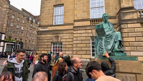 tourists gather around david hume statue in edinburgh